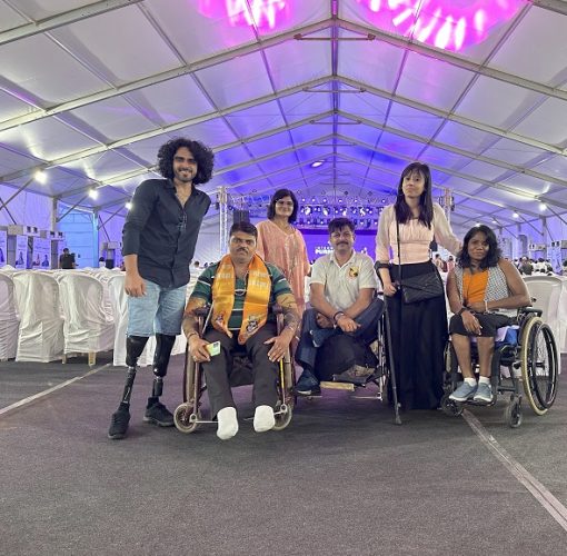 Tinkesh with two fellow TAF members alongside individuals using wheelchairs in a brightly lit room.
